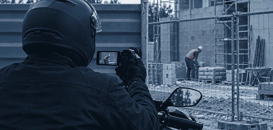 Enquêteur à moto documentant une activité professionnelle sur un chantier, scène illustrative.